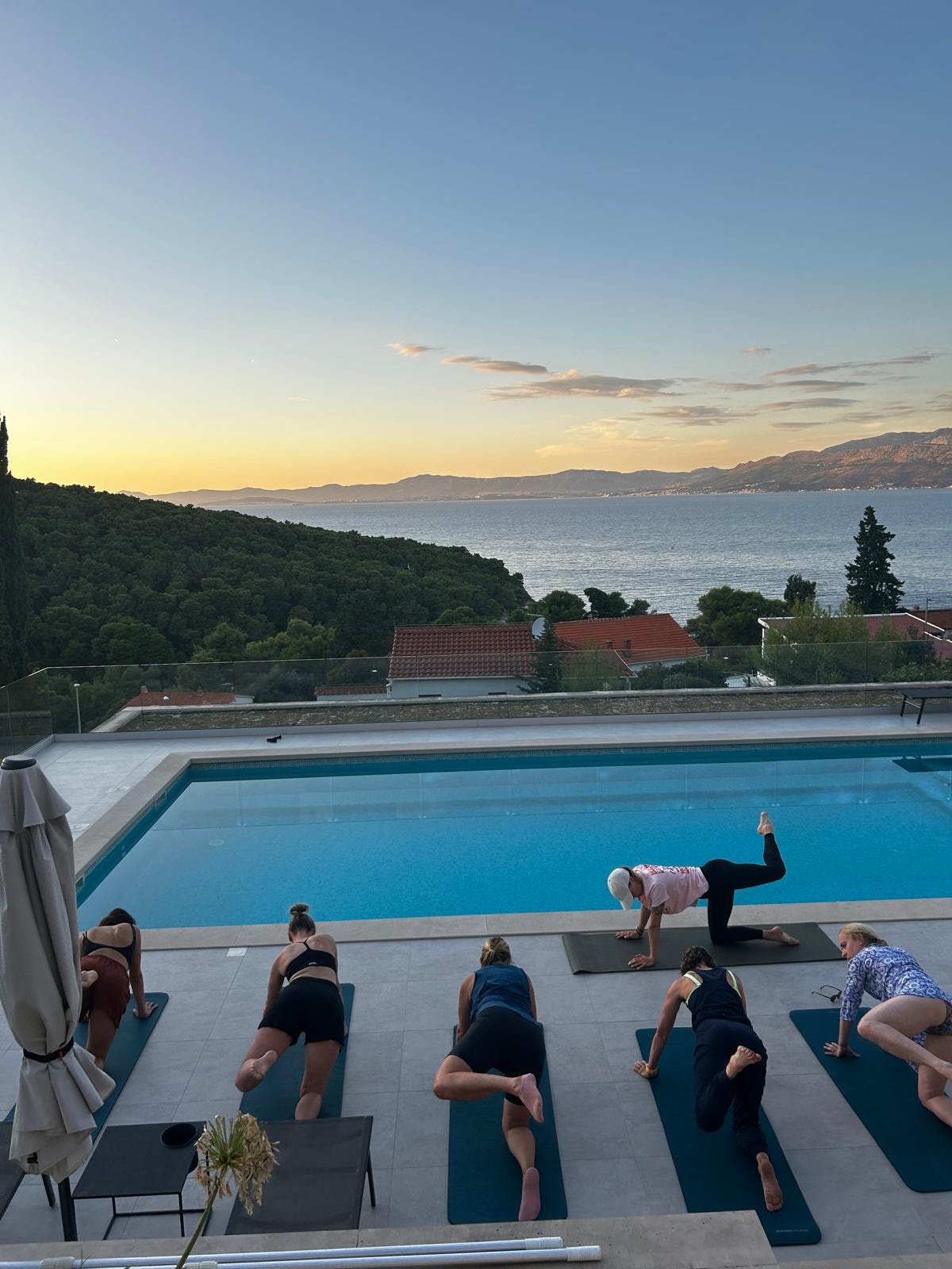 Evening Pilates class by the pool at sunset