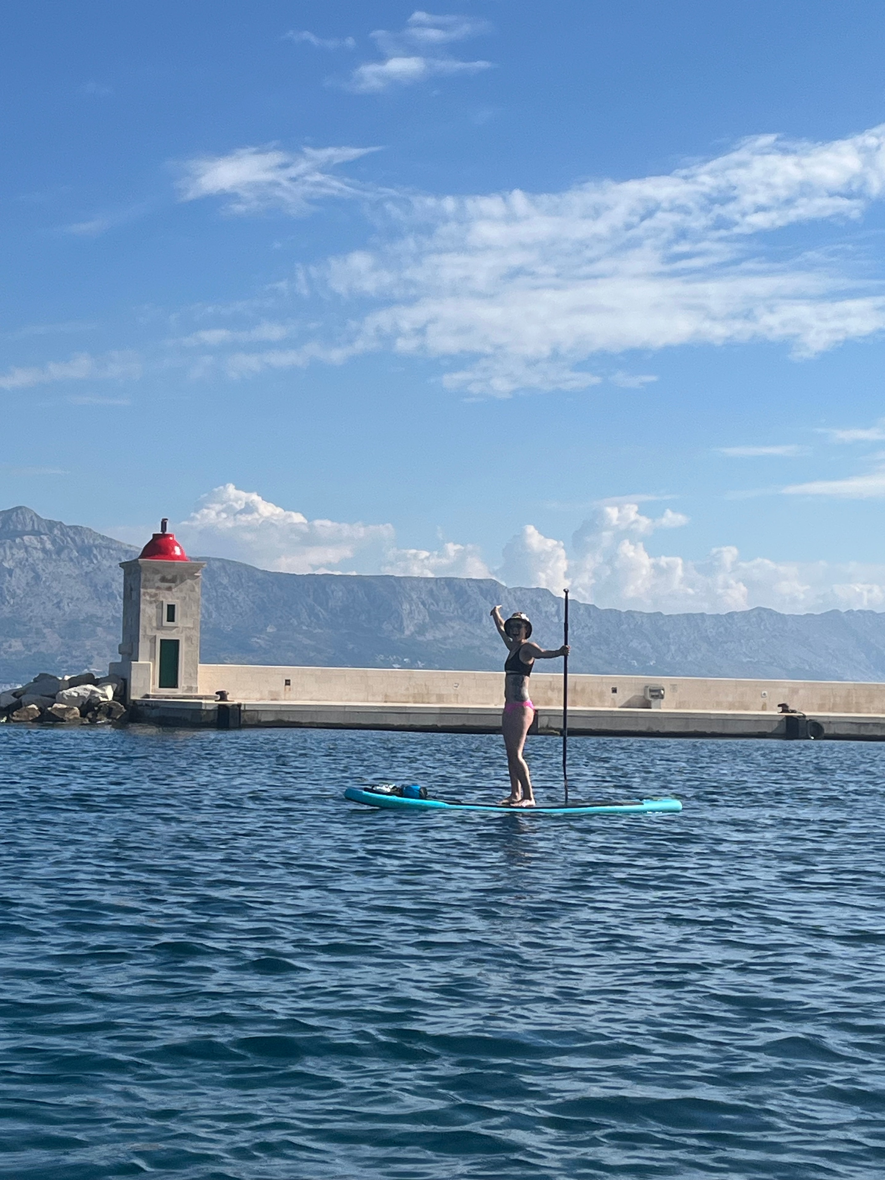 Paddleboarding by the lighthouse with mountain backdrop